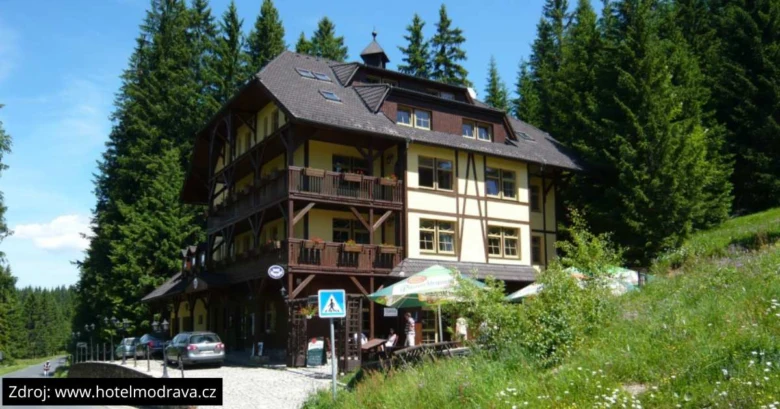 Tradiční horský hotel v Modravě na Šumavě mezi borovicemi.