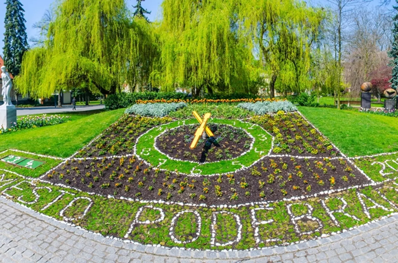 Velký květinový ciferník v Poděbradech na trávníku.