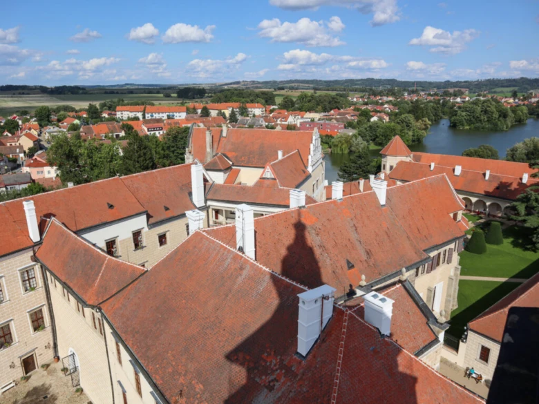 Pohled na střechy hradu v Telči s městem a jezerem.