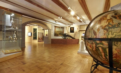 Vnitřek muzea s velkou zemí kouolí a historickým dělem.