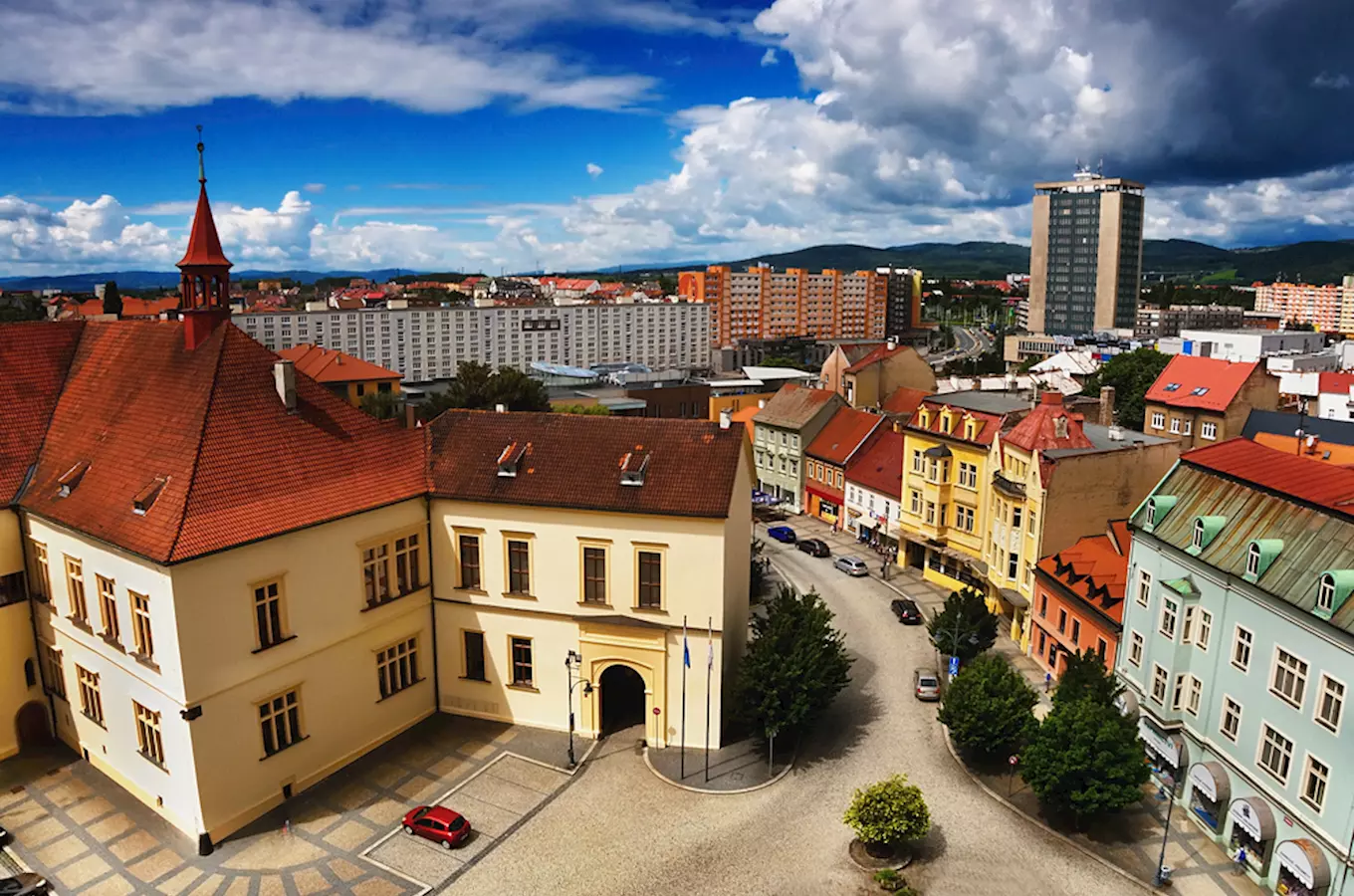 Pohled na náměstí v Chomutově s barevnými domy a historickými budovami.