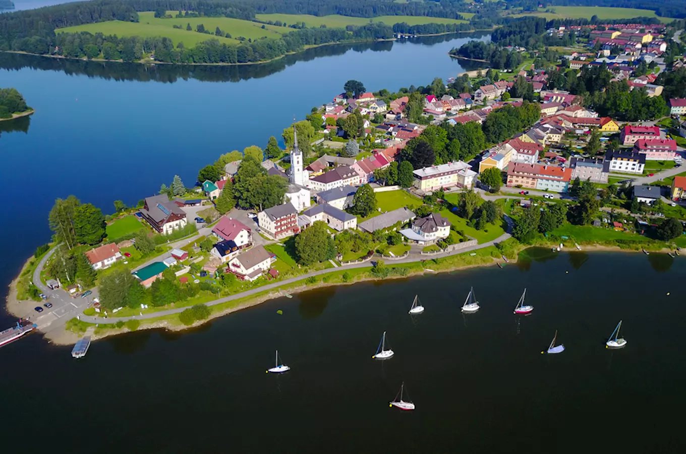 Pohled na městečko u jezera s loděmi a kostelem