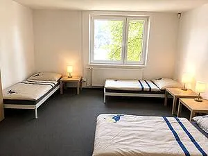 Fotografie prostorného pokoje s třemi postelemi v pražském hotelu.