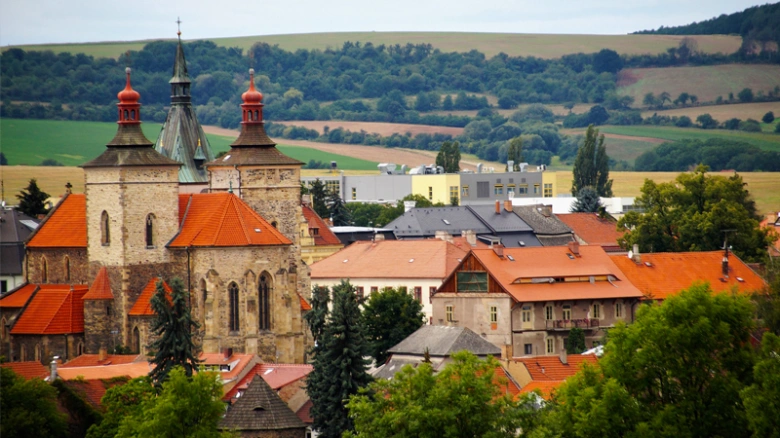 Staré město s kostely a červenými střechami v krajině.