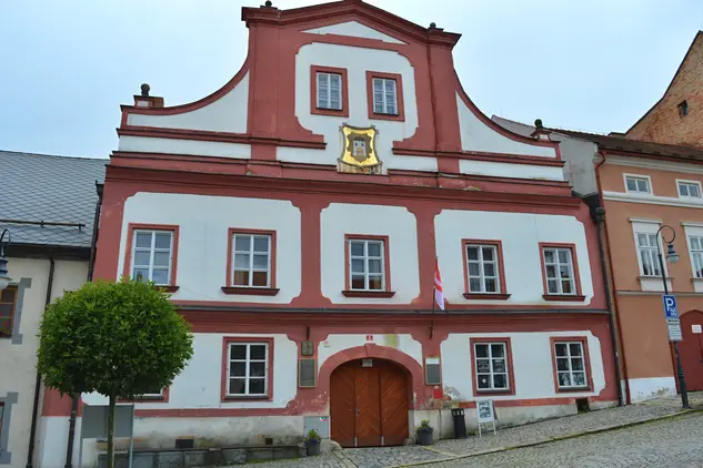 Historická budova radnice ve Vimperku s červenými fasádami.