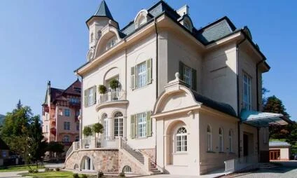 Historická vila v centru Karlových Varů s balkony a schodištěm.