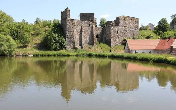 Zřícenina hradu Tábor u vody s odrazem v hladině.