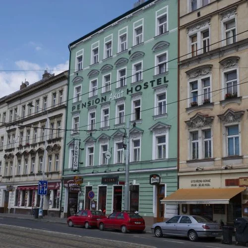 Zelený hotel v Praze s parkovanými auty před budovou.