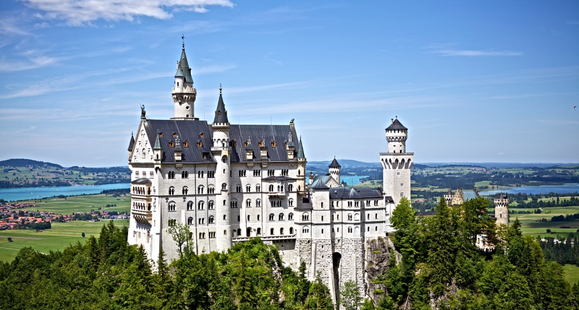 Bílé hrad Neuschwanstein na kopci s výhledem do krajiny.
