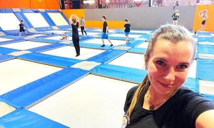Žena se fotí na trampolínové hřišti s ostatními návštěvníky.