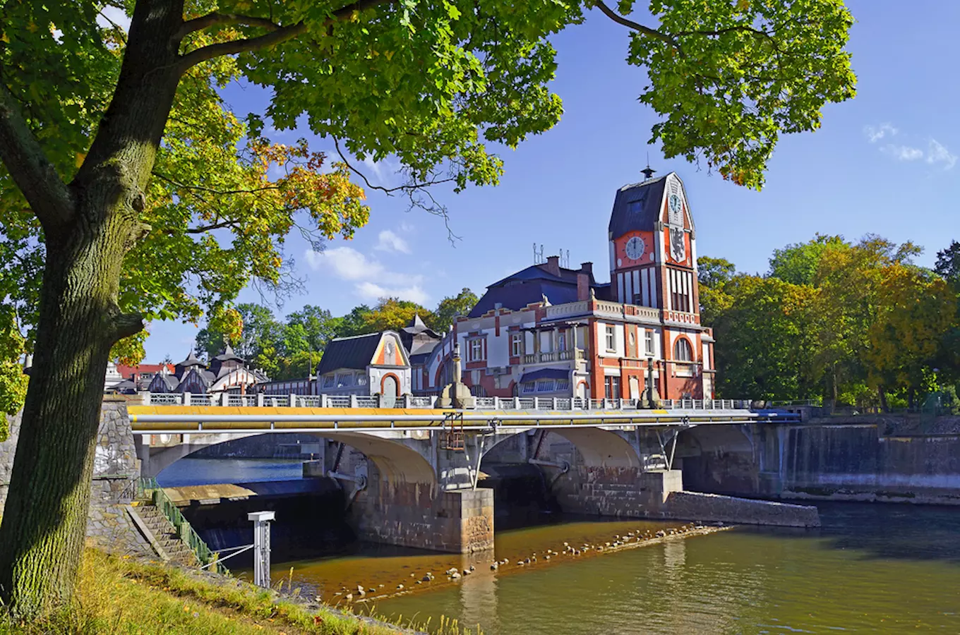 Historická věž s hodinami mostem nad řekou v Hradci Králové.