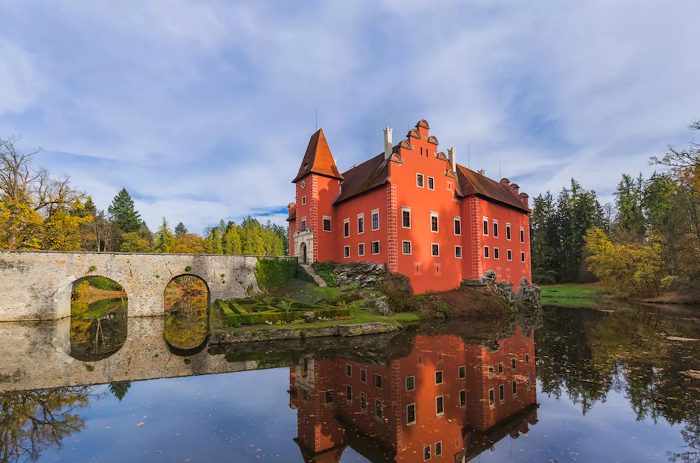 Červený hrad na ostrově s odrazem ve vodě.