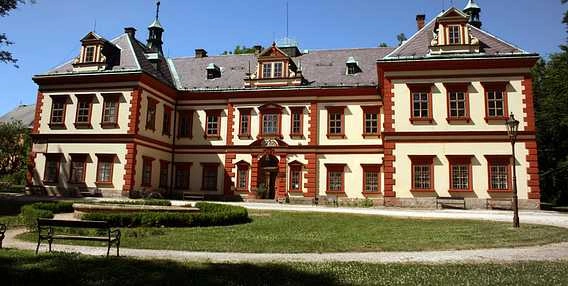 Historická budova ve Vrchlabí s červenými proužky na fasádě.