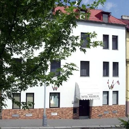 Bílá budova hotelu Vodní v Praze s červenou střechou.