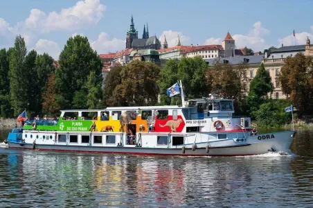 Barva na řece v Praze s historickými budovami.