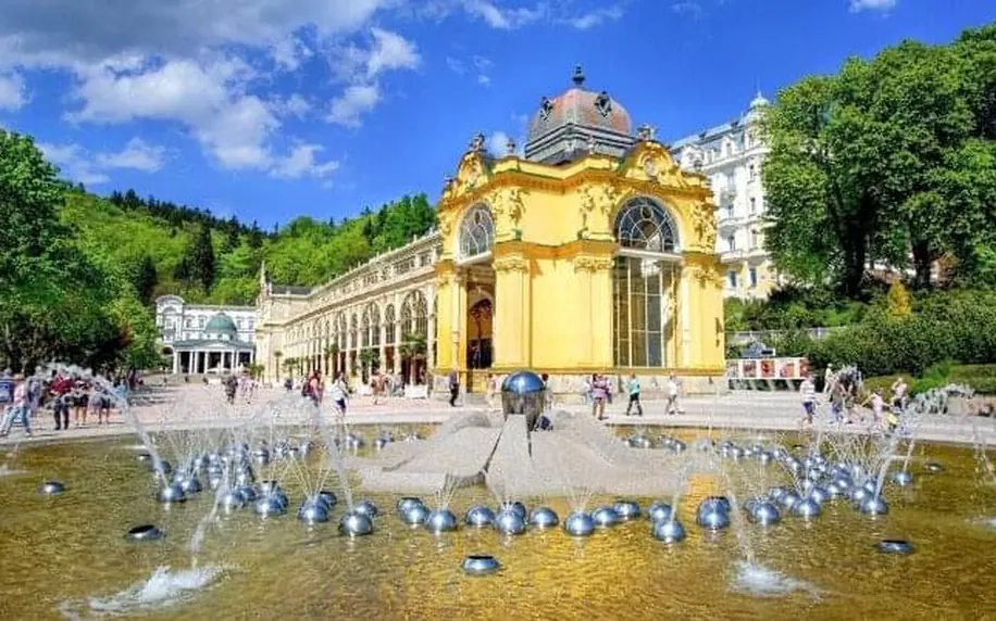 Žlutá lázeňská budova s fontánou v parcích