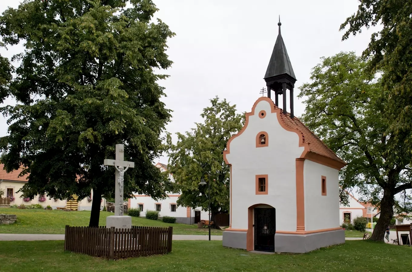 Malý kostelík s věžičkou a křížem na návsi v Holašovicích
