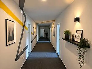 Moderní chodba v pražském hotelu s uměleckými díly a rostlinami.