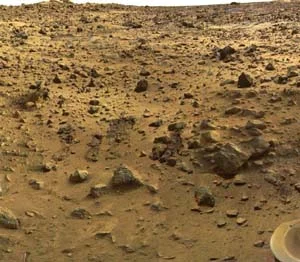 Povrch planety Mars s kameny a červenou půdou.