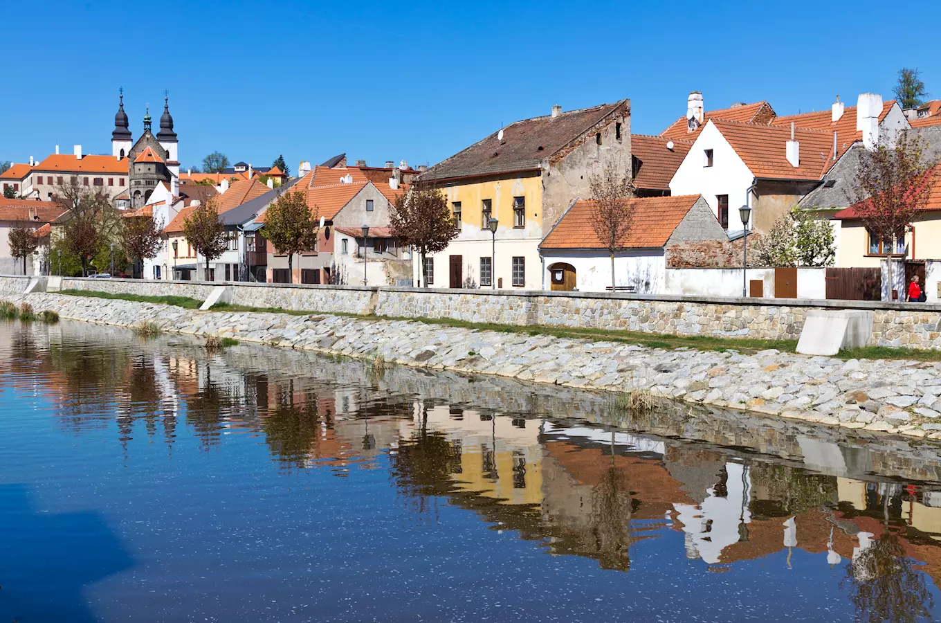 Pohled na řeku v Třebíči s historickými domy odrazem ve vodě.