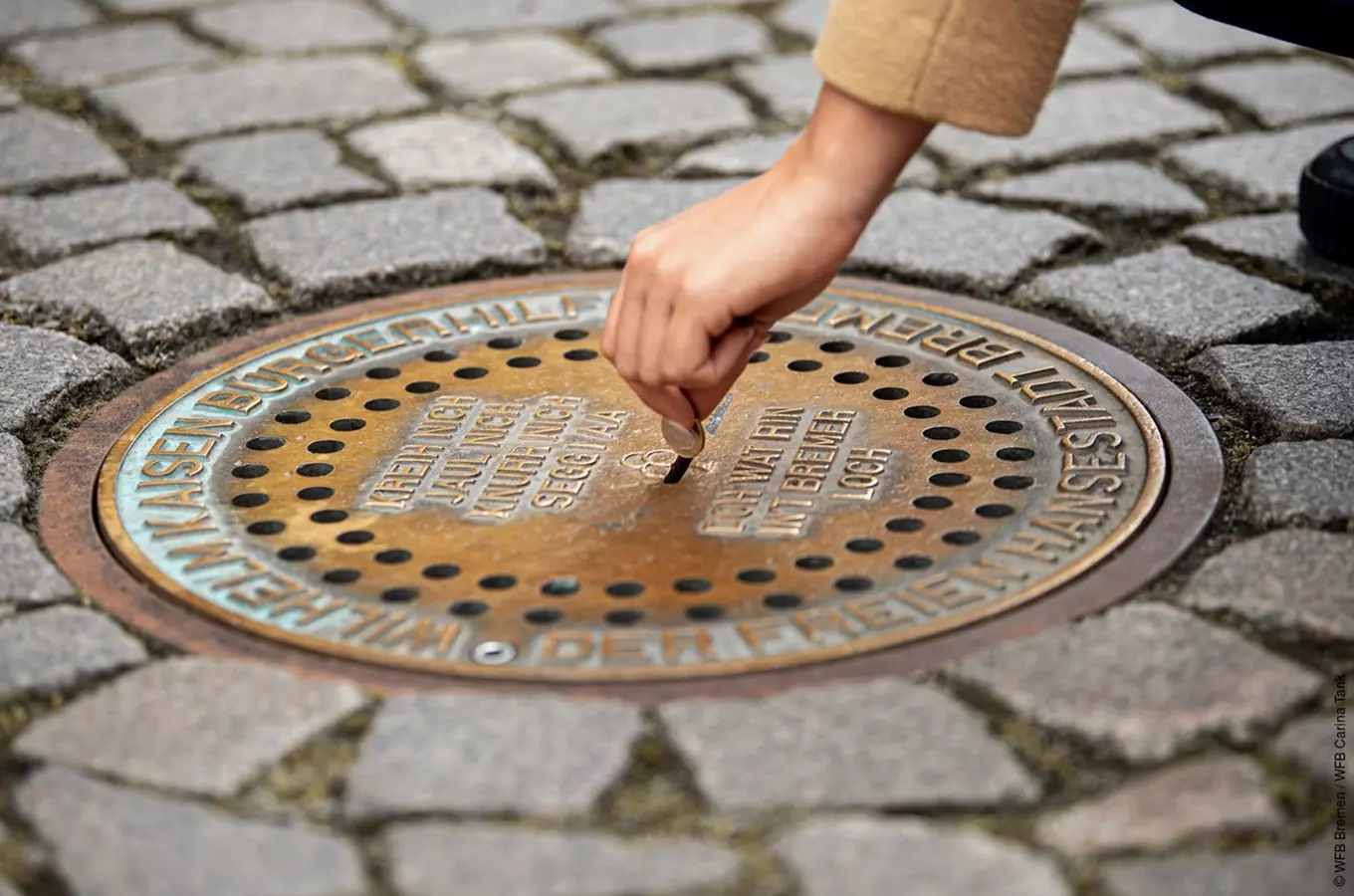 Ruka vkládá minci do historického poklopů v německém Braunschvigu.